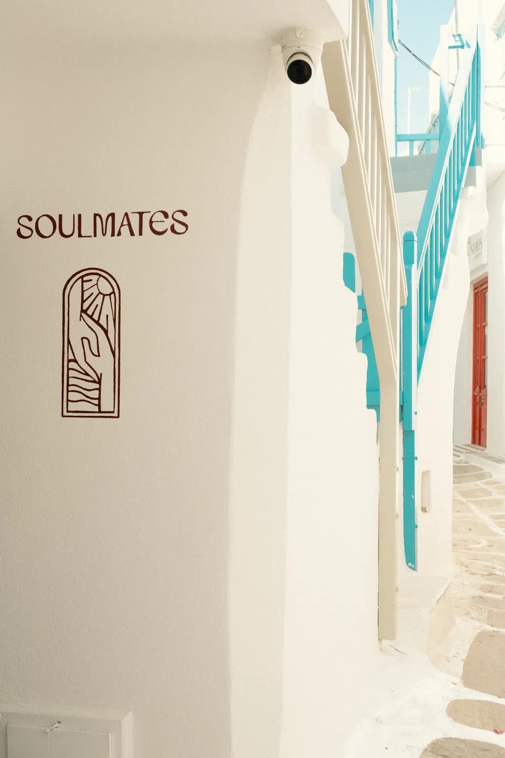 The whitewashed alley entrance to Soulmates, with the red hand-painted logo on the corner wall